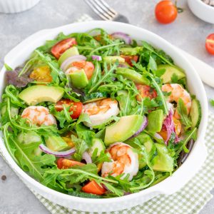 salad with prawns, tomatoes, avocado, cucumber and onions in a bowl. Healthy dish.